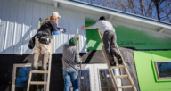 Contractors install the siding on a new house, one of the many steps to building a house.